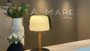A reception desk with a modern lamp, a vase with flowers, and a wall with the hotel name 'A. MARE HOTEL'. - A.Mare Hotel (Eraclea Mare)