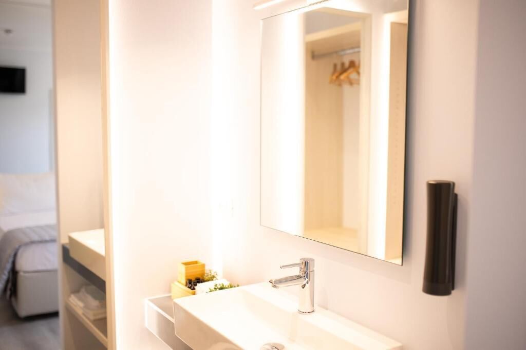 A modern bathroom with a white sink, a mirror, and a towel rack.