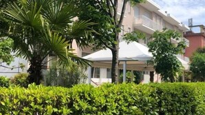 A building with a balcony, a palm tree, and a hedge. - A.Mare Hotel (Eraclea Mare)