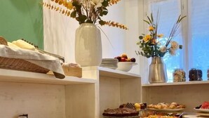 A buffet with various food items, a vase with flowers, and a window with a view. - A.Mare Hotel (Eraclea Mare)