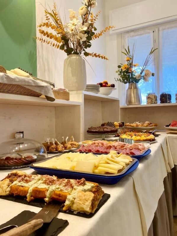 A buffet with various food items, a vase with flowers, and a window with a view.