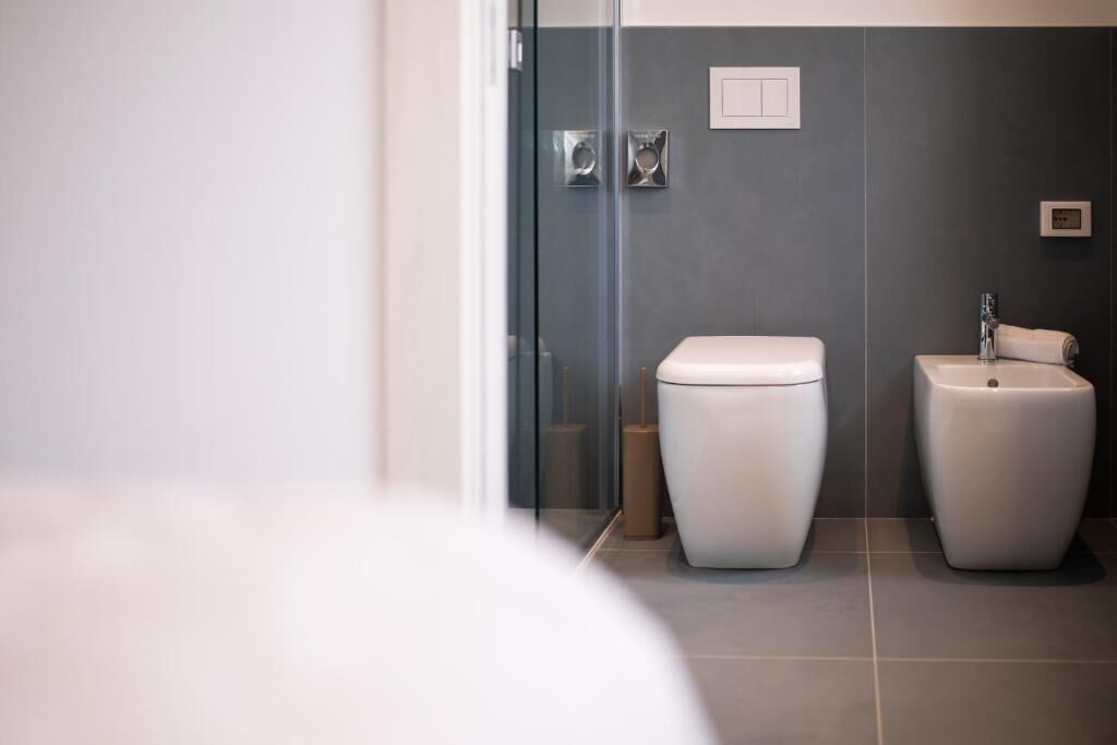 A modern bathroom with a toilet, bidet, and glass shower enclosure.