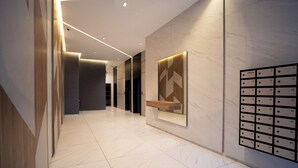 Ein moderner Hotelkorridor mit Marmorboden, einer an der Wand befestigten Zimmernummer und einem Holzregal.