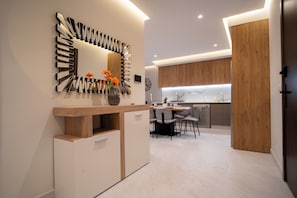 A modern kitchen with a wooden cabinet, a built-in oven, and a dining area with a table and chairs. - 2-bedroom apartment with terrace,  minutes to shopping, train, restaurants. (Tangier)