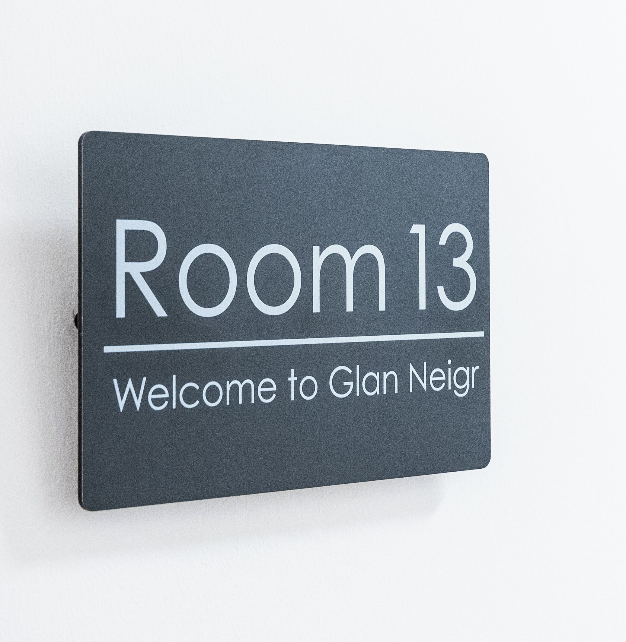 Segnaletica con la scritta 'Room 13' e 'Welcome to Glan Neir', che indica il numero e il nome della stanza.