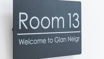 Señal con la inscripción 'Habitación 13' y 'Bienvenido a Glan Neir', indicando el número y nombre de la habitación.