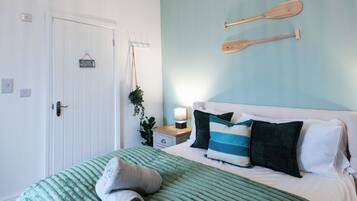 Una camera da letto con un letto, un comodino, una tavola da surf appesa al muro e una porta con un cartello.