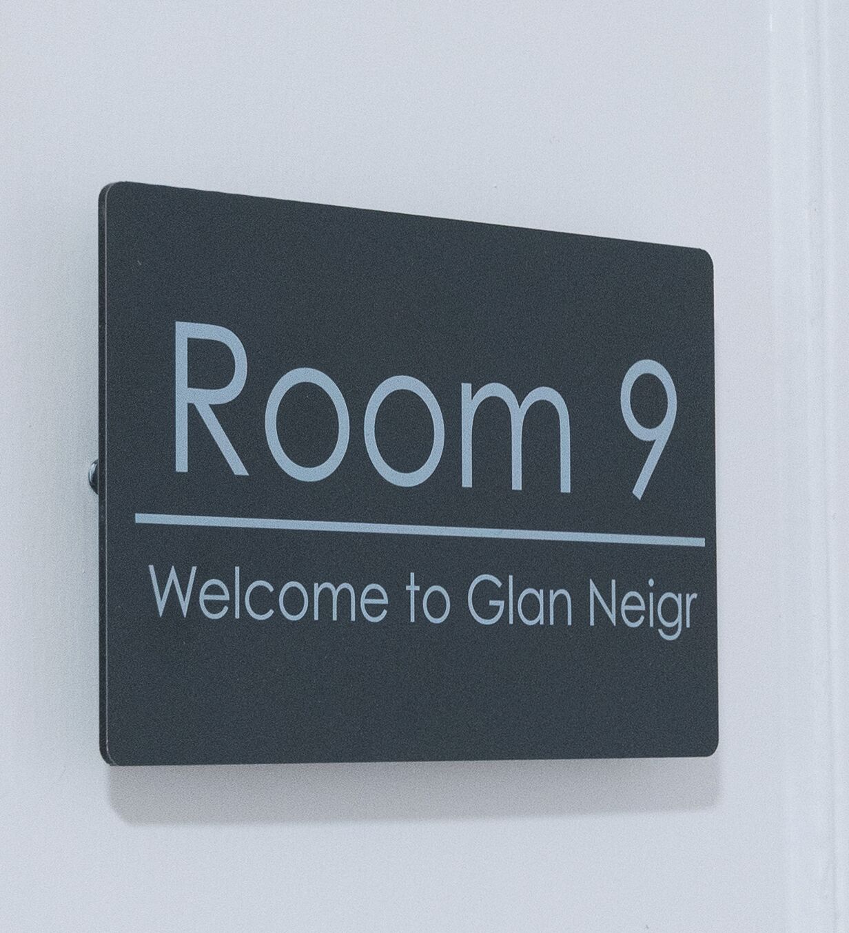 A sign indicating 'Room 9' with a welcome message to 'Glan Neir'.