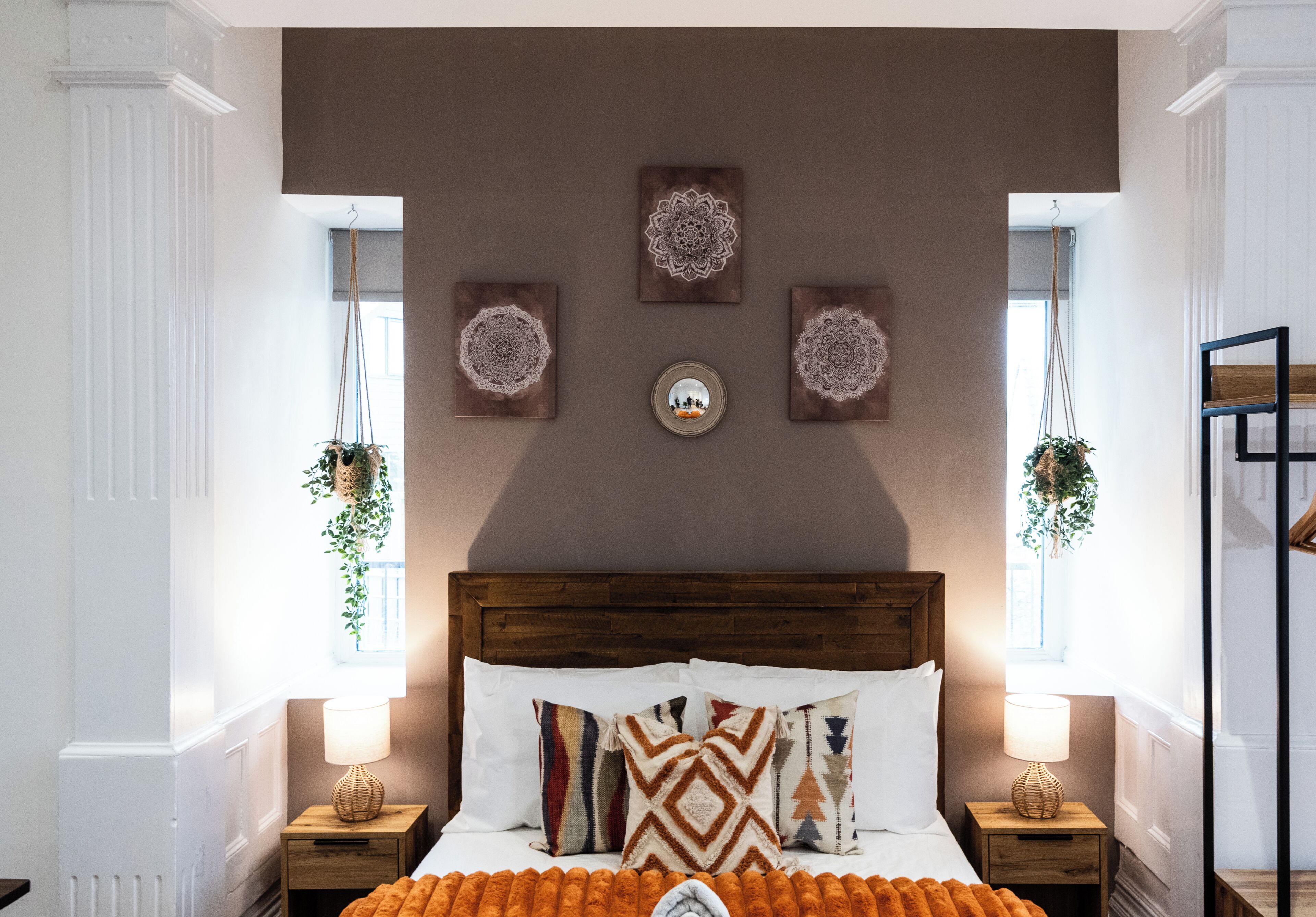 A bedroom with a wooden headboard, a bed with patterned pillows, bedside tables with lamps, and wall decor.