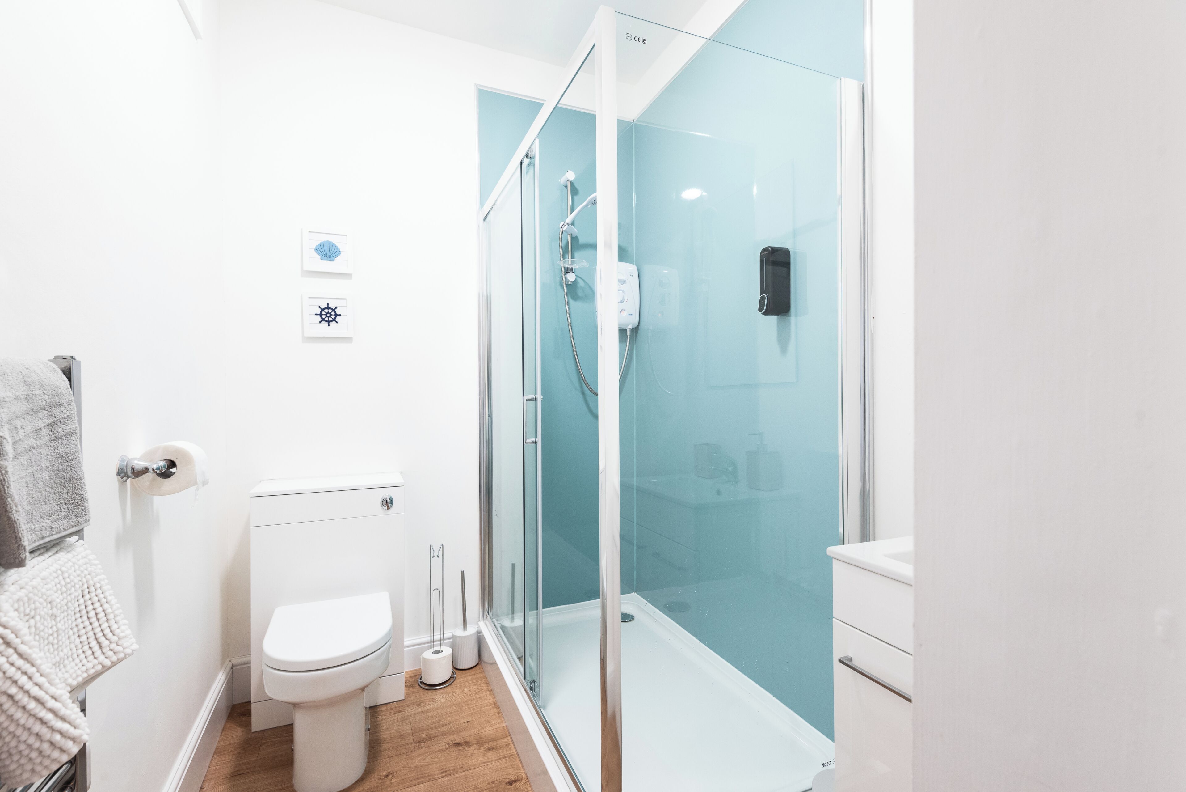 Un baño moderno con inodoro, cabina de ducha y perchero.
