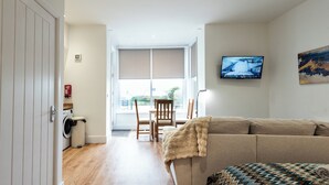 Una habitación con sofá, televisor, ventana y lavadora.