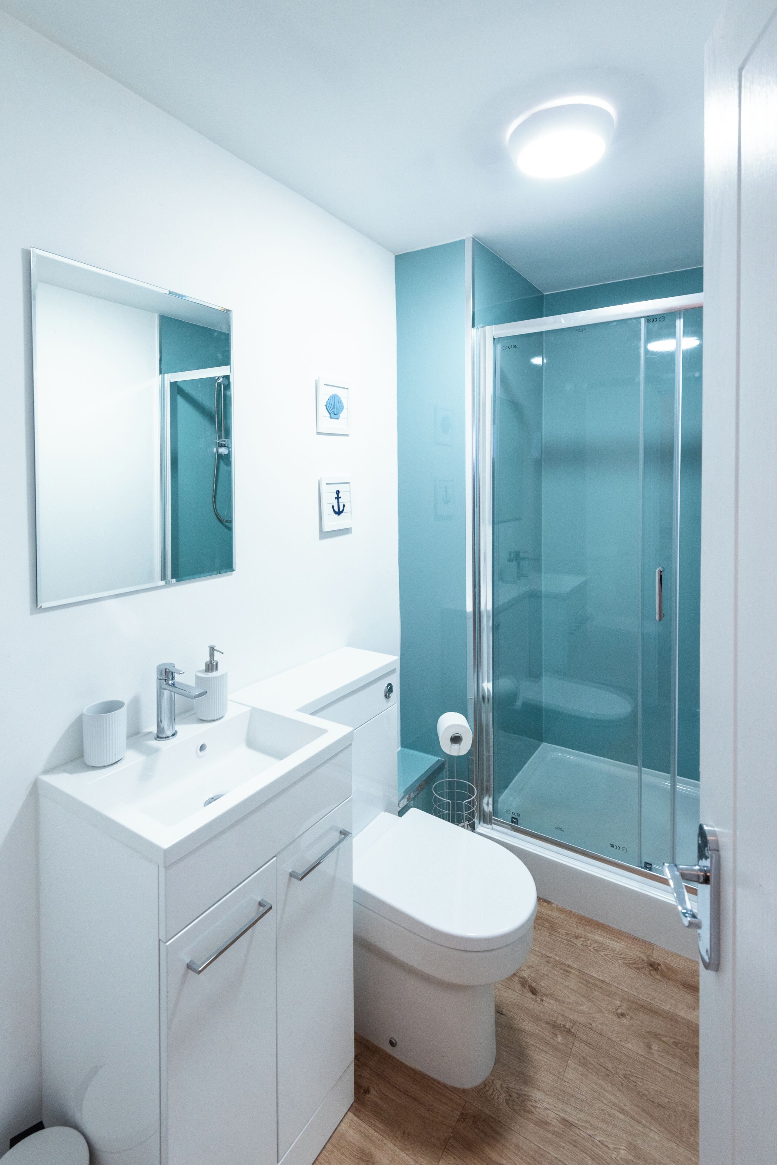 Un baño moderno con cabina de ducha de vidrio, un lavamanos blanco y un inodoro.