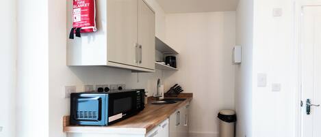 A compact kitchen with a microwave, sink, and cabinets.