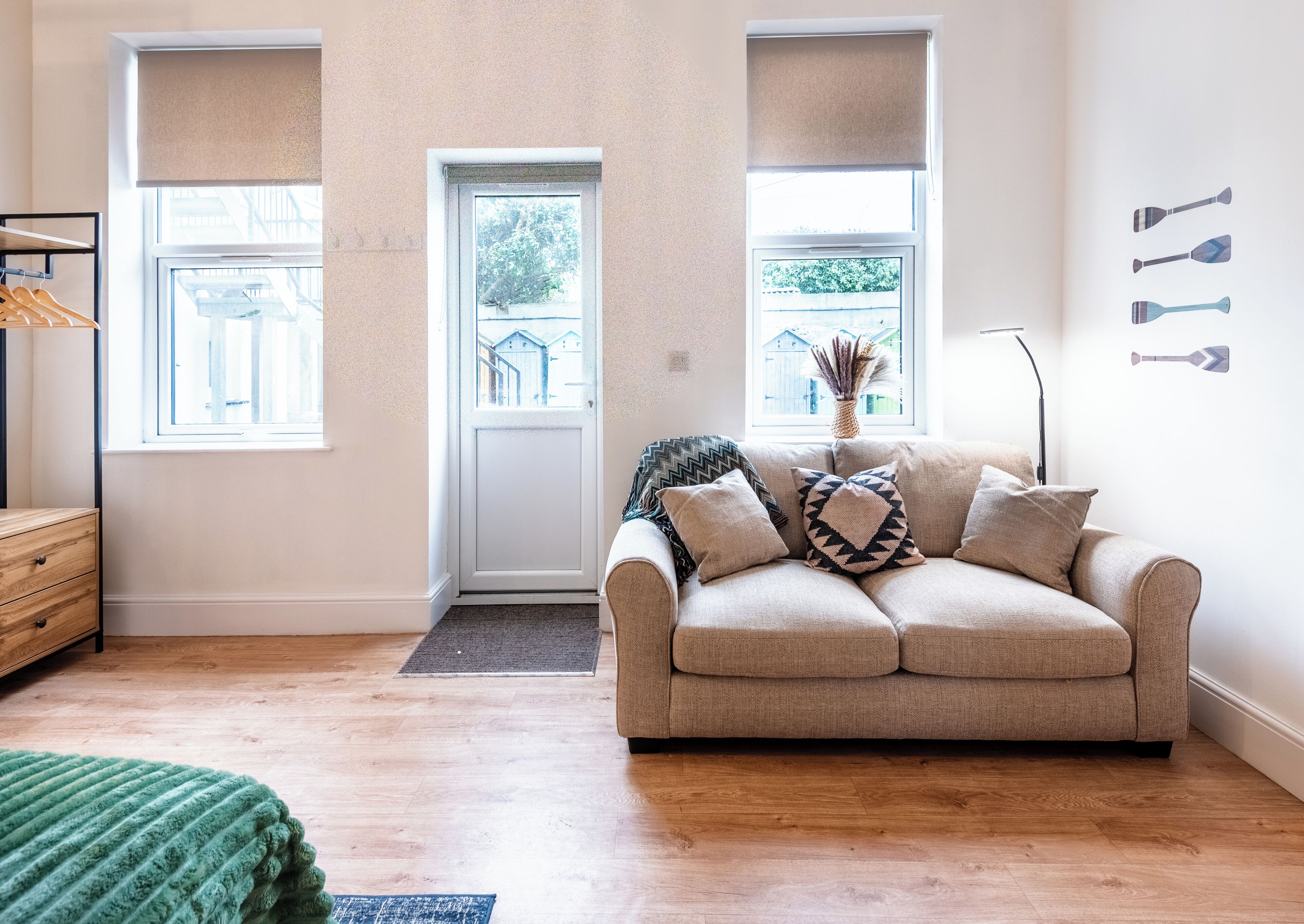 Ein Wohnzimmer mit einem beigen Sofa, einem Holzschrank und einem grünen Teppich.