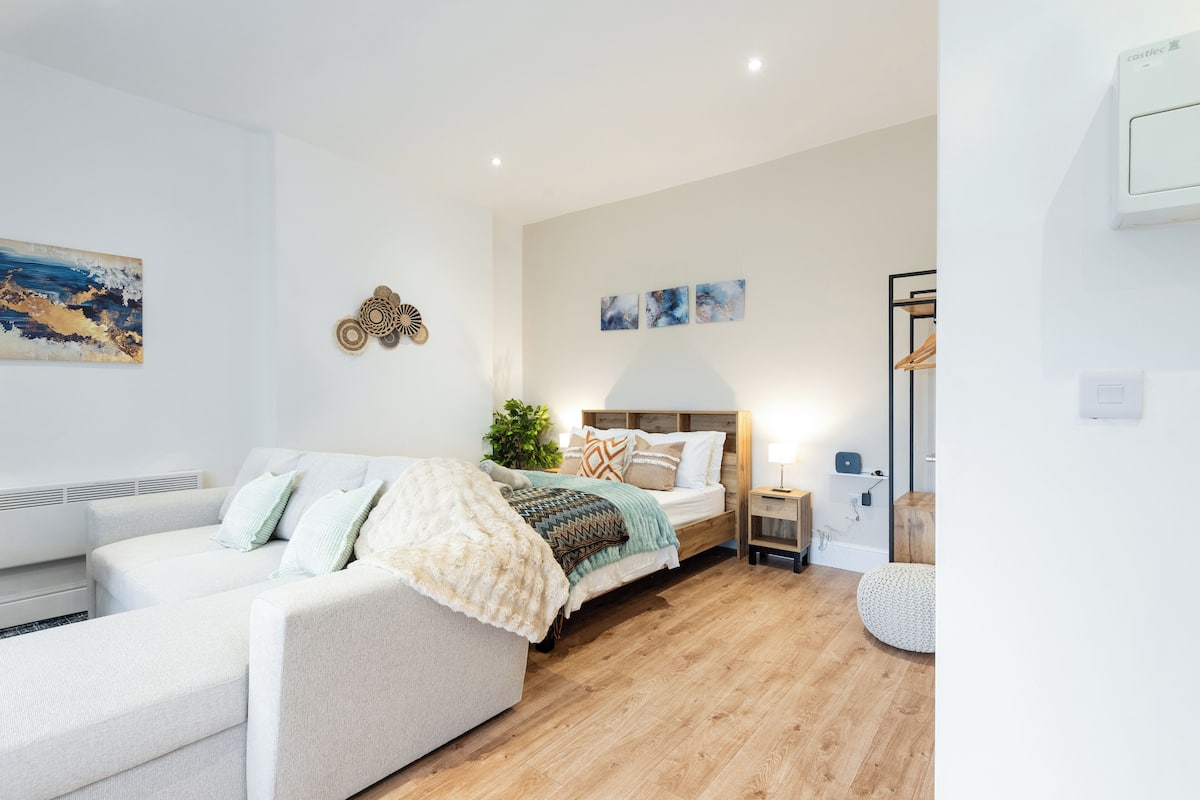 Un dormitorio moderno con cama, sofá, mesita de noche y lámpara.