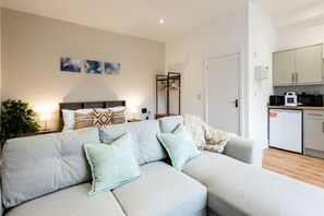 A modern living room with a sofa, pillows, and a small side table.