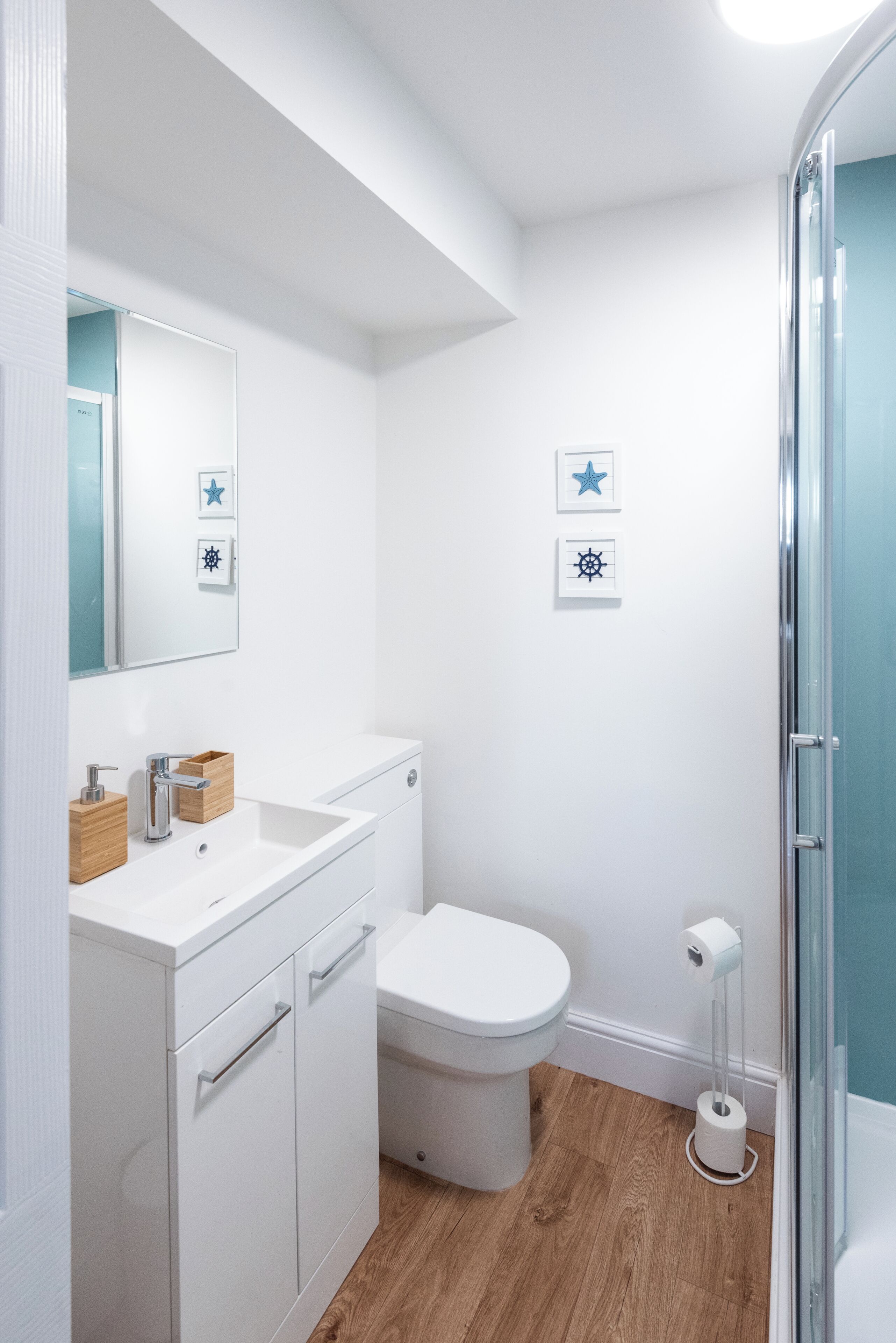 Een moderne badkamer met een witte wastafel, toilet en douche.