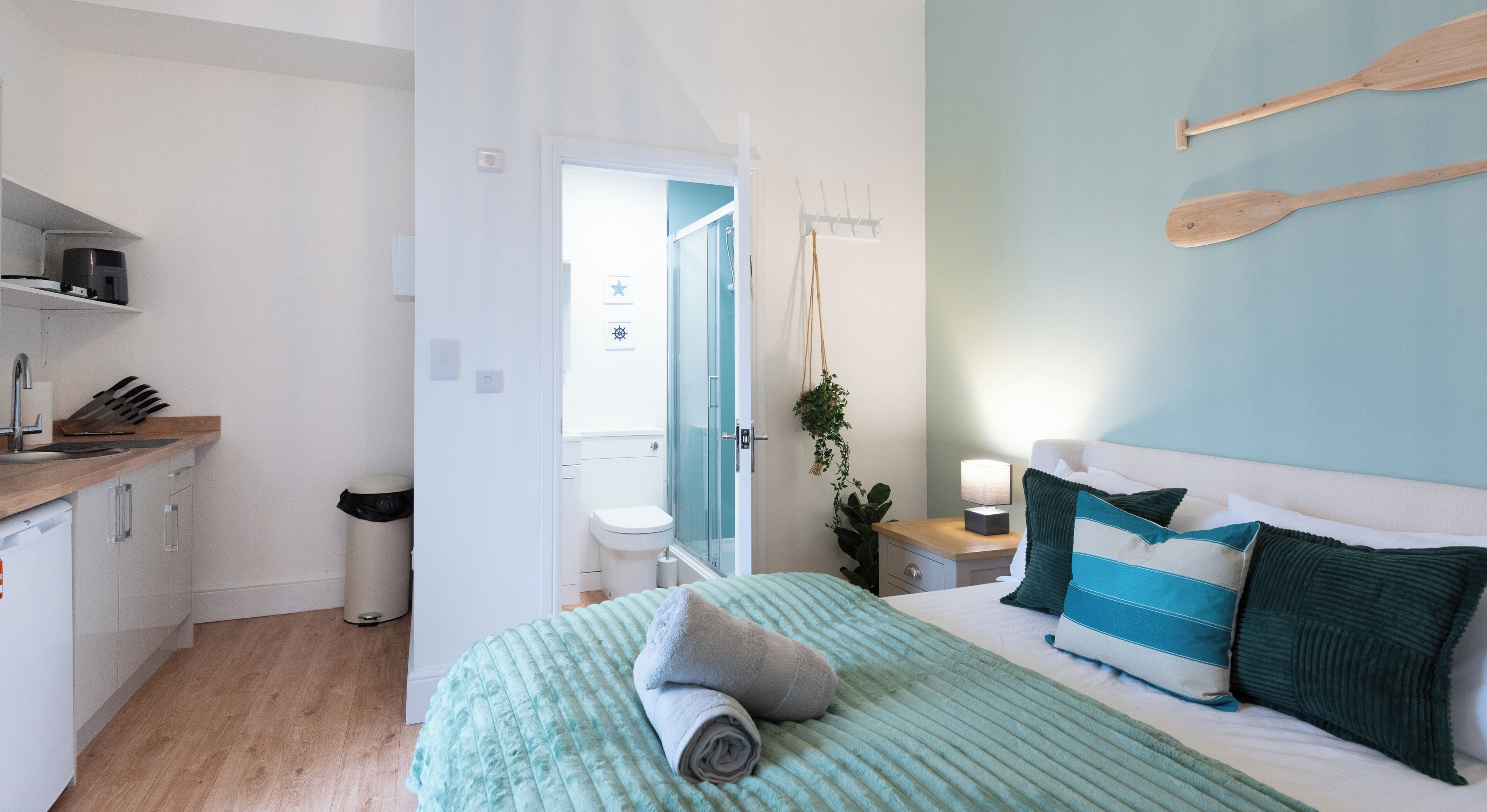 A bedroom with a bed, bedside table, and a view into the bathroom.