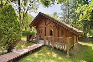 Eine Holzjagdhaus mit Veranda, einer kleinen Terrasse und einem Berg im Hintergrund.
