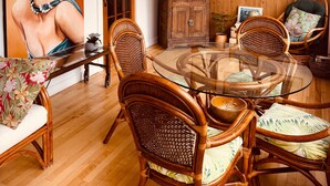 A dining area with wicker chairs, a glass table, and a large painting on the wall. - L'Élégante Centenaire de Matane (Matane)