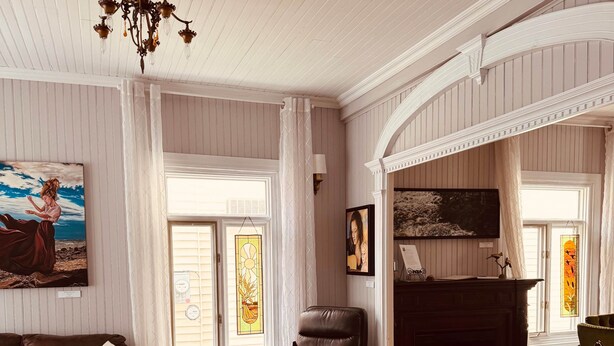 A living room with a fireplace, leather furniture, and a chandelier. - L'Élégante Centenaire de Matane (Matane)