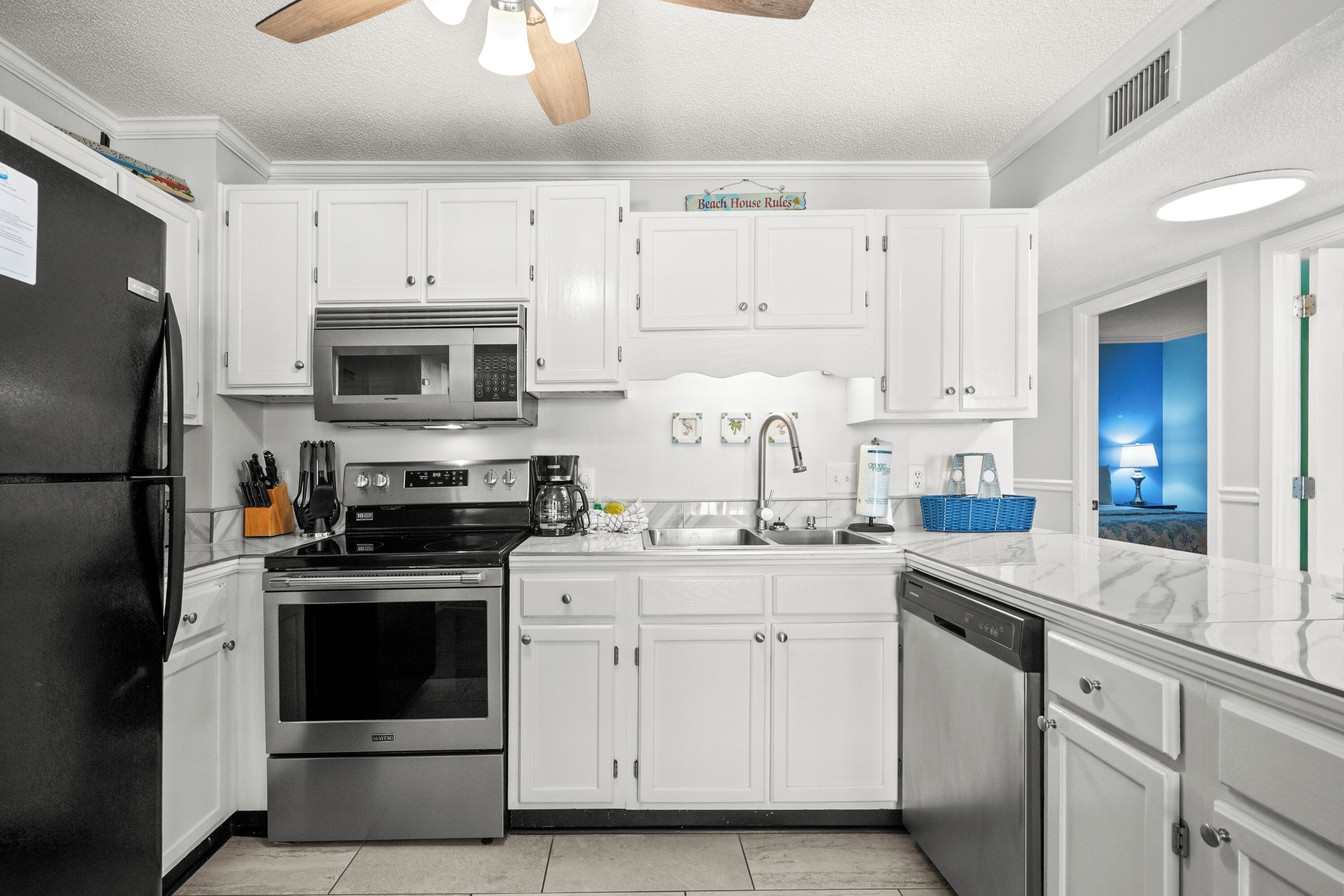 Una cucina moderna con mobili bianchi, elettrodomestici in acciaio inossidabile e una parete di accent blu.