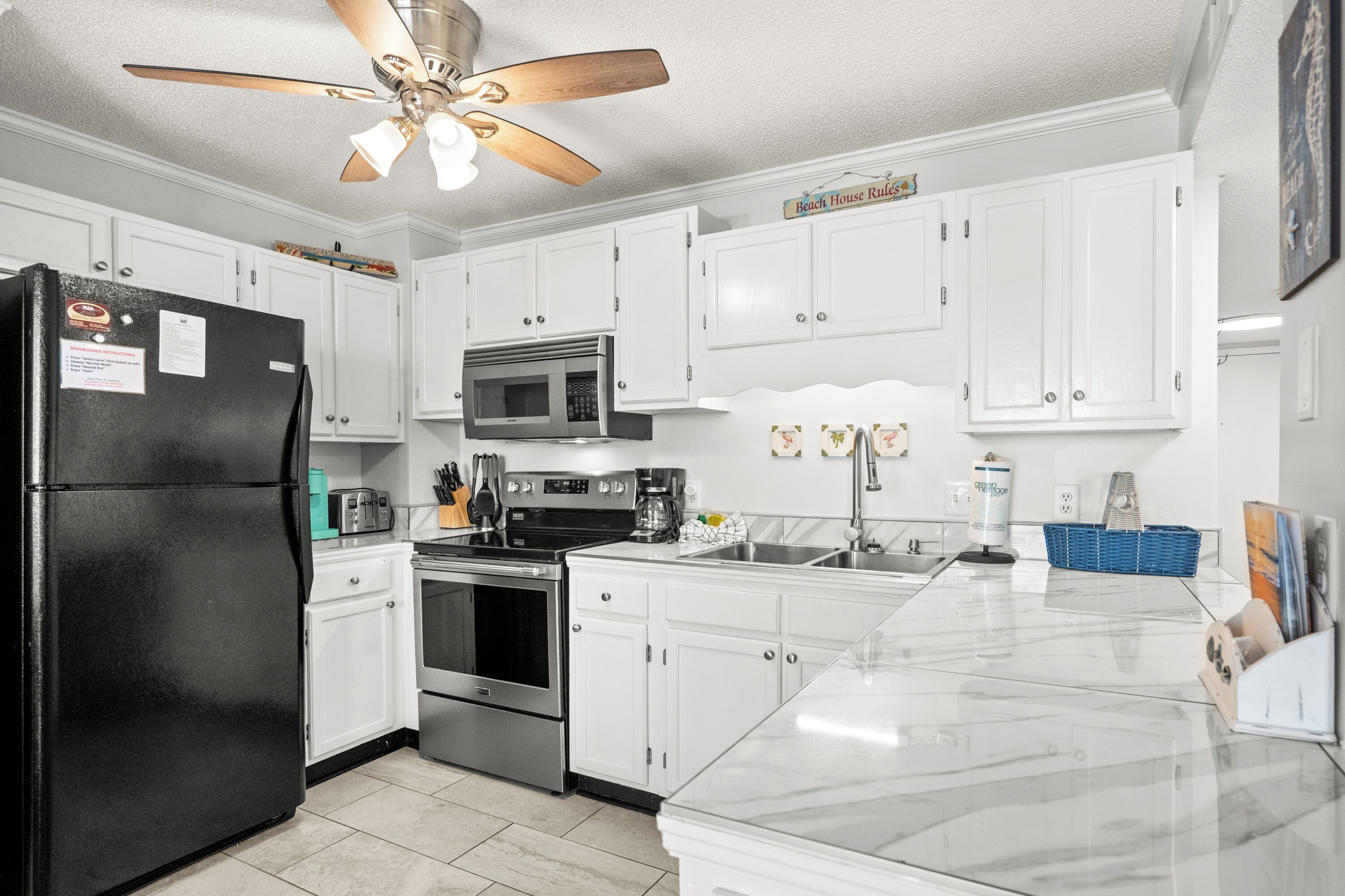 A modern kitchen with white cabinets, stainless steel appliances, and a marble countertop.