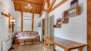 Una habitación acogedora con techo y banco de madera, una mesa con taburetes y estantes en la pared.