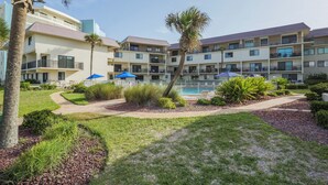 Ein Hotel mit mehreren Balkonen, einem Schwimmbad und gepflegter Gartenanlage.