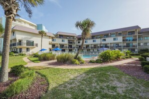 A hotel with multiple balconies, a swimming pool, and well-maintained landscaping. - Bent Palm 302 | Romantic Condo + Remodeled Touches (Ormond Beach)
