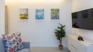 Een moderne woonkamer met een bank, een potplant en drie schilderijen van Claude Monet aan de muur.