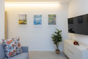 A modern living room with a sofa, a potted plant, and three Claude Monet paintings on the wall. - Sivori Apartment (Rome)