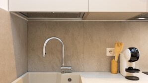 Een keuken met een moderne gootsteen, een kraan, een houten spatel en een koffiezetapparaat.