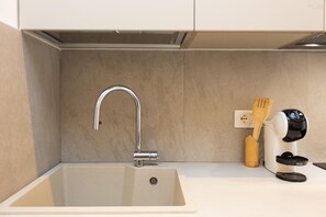 A kitchen with a modern sink, a faucet, a wooden spatula, and a coffee maker. - Sivori Apartment (Rome)
