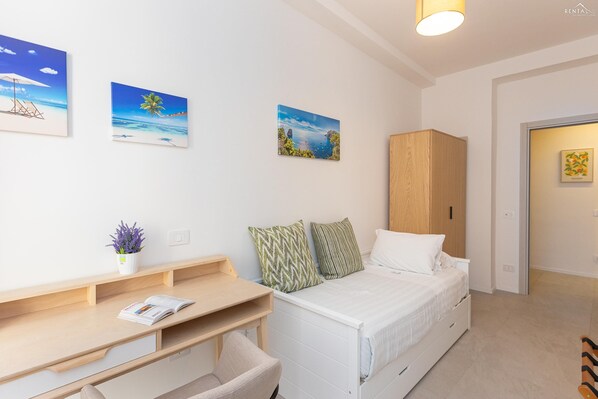 A bedroom with a bed, a desk, a chair, a wardrobe, and two wall-mounted paintings. - Sivori Apartment (Rome)