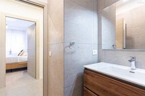 Ein modernes Badezimmer mit großem Spiegel, Waschbecken und Duschbereich.