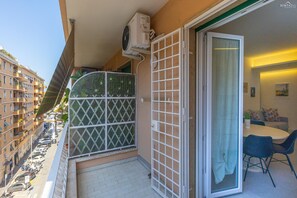 Ein Balkon mit einer Glasschiebetür, einem weißen Gitter und einem kleinen Tisch mit Stühlen.