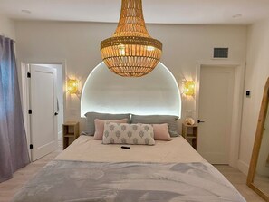 A bedroom with a large bed, a unique ceiling design, and two wall-mounted lamps. - Coastal Pearl | Walk to Beach | Heated Pool + Hot Tub | 4BR Family Retreat (Holmes Beach)
