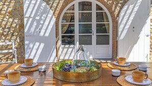 Una mesa dispuesta con un centro de mesa, puertas blancas y una pared de piedra.