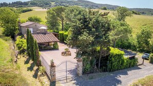 Una propiedad rural con una casa de piedra, un jardín vallado y un camino de entrada de grava.