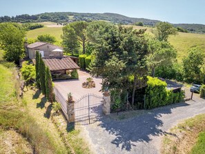 Une propriété située en zone rurale, comprenant une maison en pierre, un jardin clôturé et une allée gravillonnée.