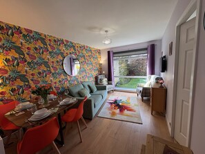 Een eetgedeelte met een tafel voor vier personen, een bank en een groot raam met uitzicht op de omgeving.