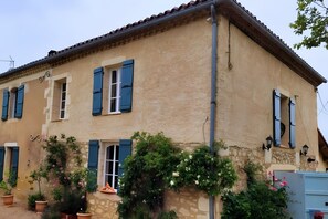 A two-story building with blue shutters, stone walls, and potted plants. - Peace at the End of the Lane: Relax in a Unique Historic Winery Retreat (Jegun)
