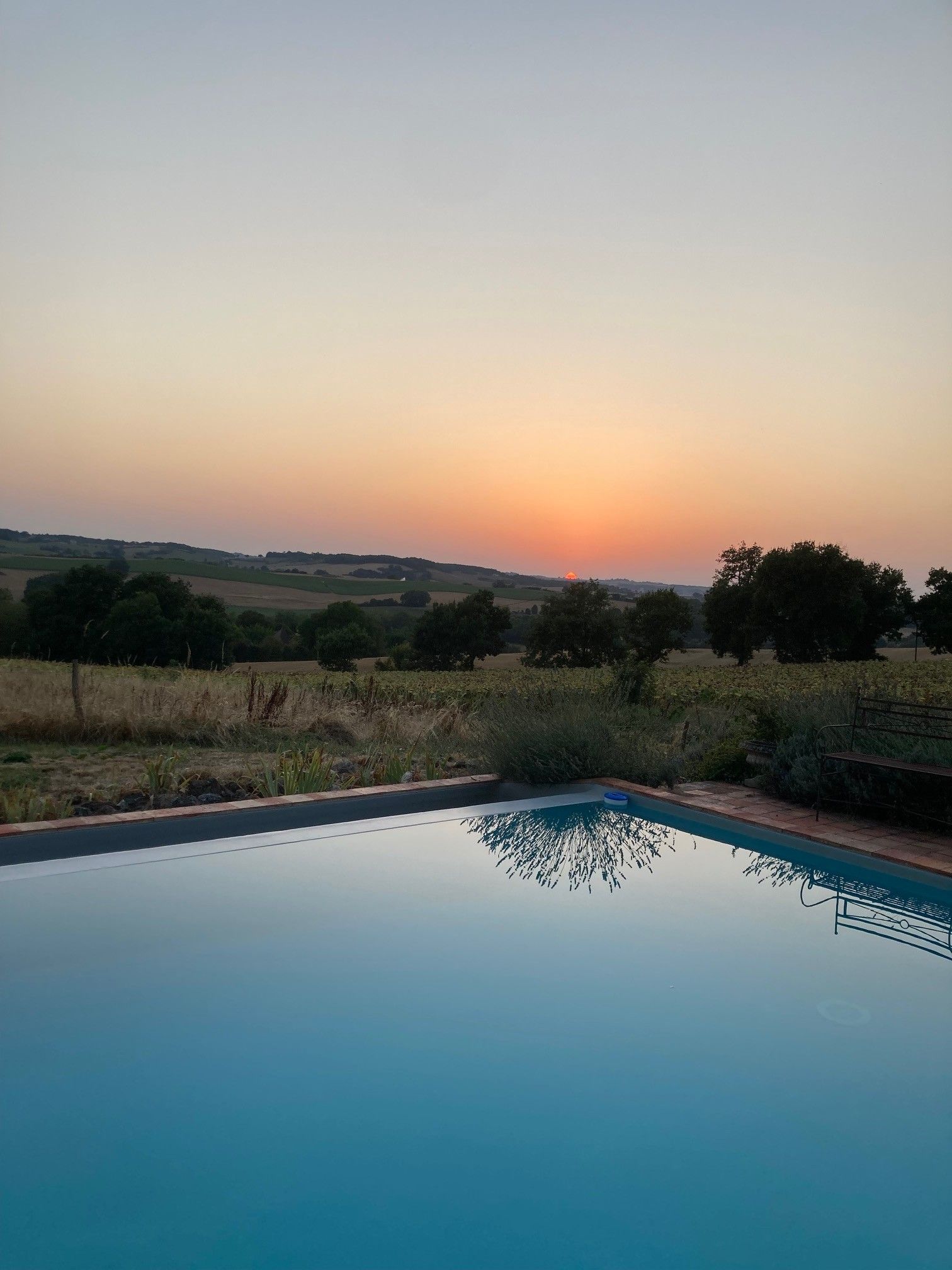 Una piscina con vista chiara sul tramonto su un paesaggio rurale.