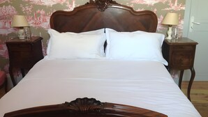 A neatly made bed with a wooden headboard, two bedside tables with lamps, and floral wallpaper. - Peace at the End of the Lane: Relax in a Unique Historic Winery Retreat (Jegun)