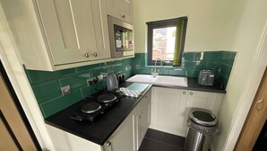 Una cocina compacta equipada con microondas, estufa, fregadero y un ventanal con cortinas.