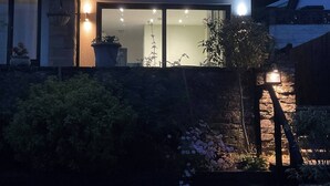 Una casa moderna con un amplio ventanal, una pared de piedra y una planta en maceta.