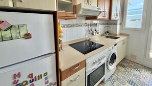 A compact kitchen with a refrigerator, stove, microwave, and sink. - Apartment Ria de Ajo 12021 (Ajo)