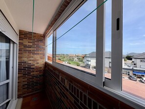 Ein Balkon mit Backsteinmauern, großen Fenstern und Blick auf eine Wohngegend.
