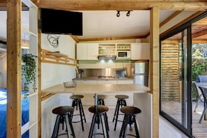 Una cocina moderna con una isla central, taburetes de bar y un televisor instalado en la pared.